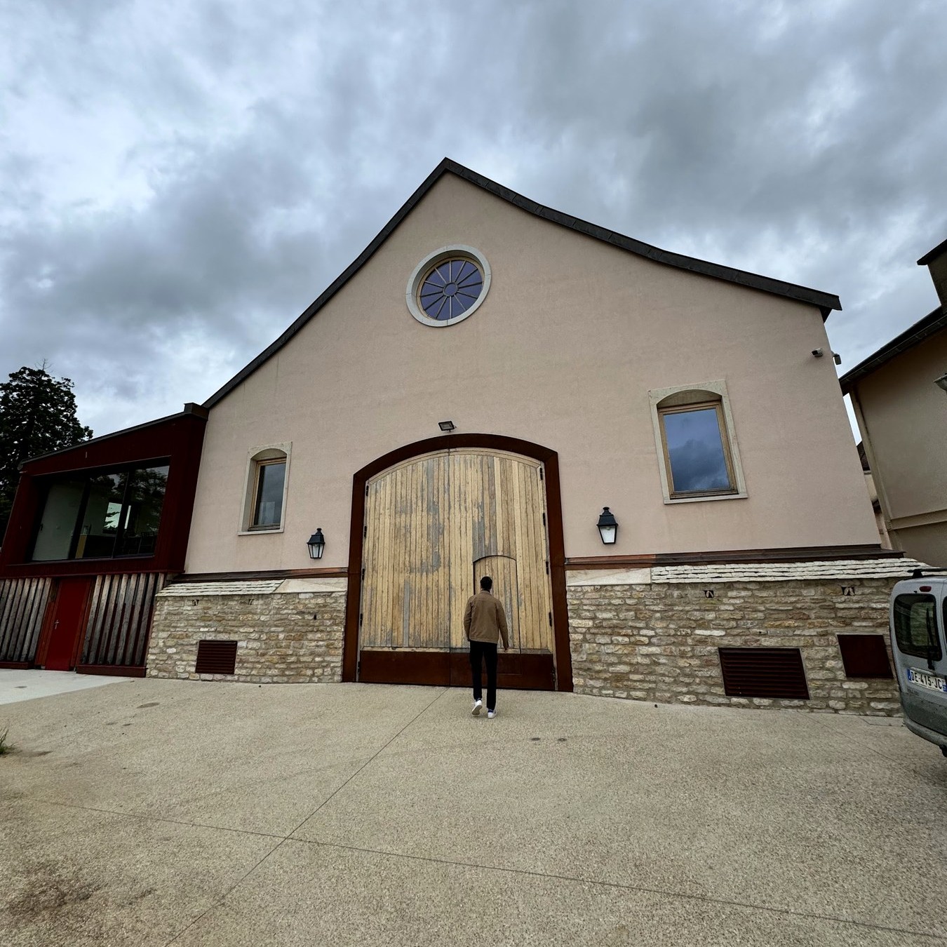 The cream-rendered winery building and arched wooden door at Domaine Dujac