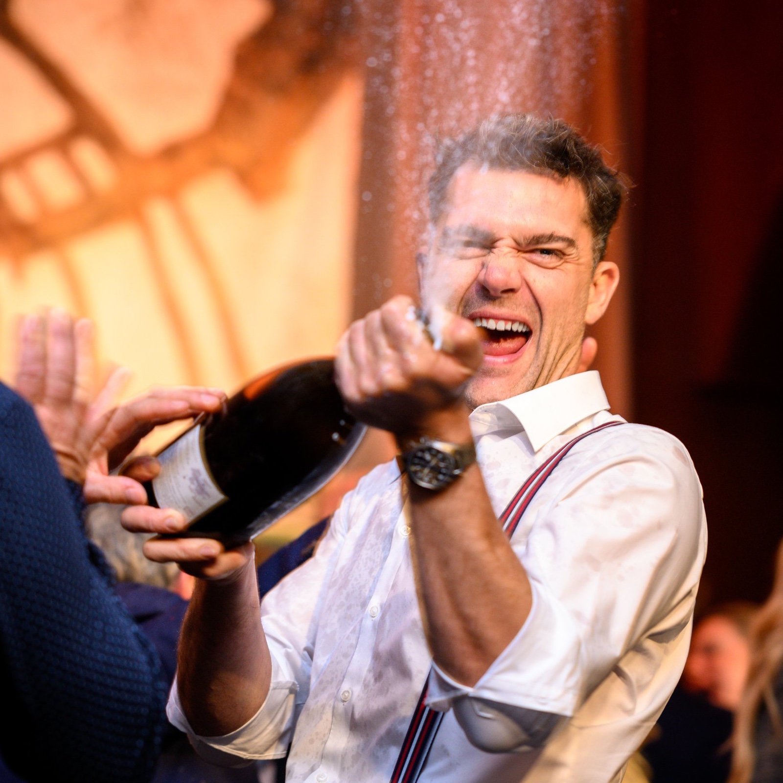 A guest sprays Champagne from a large-format bottle at an earlier La Fête gala.