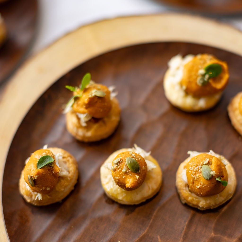 Small savory bites arranged on a wooden serving platter.