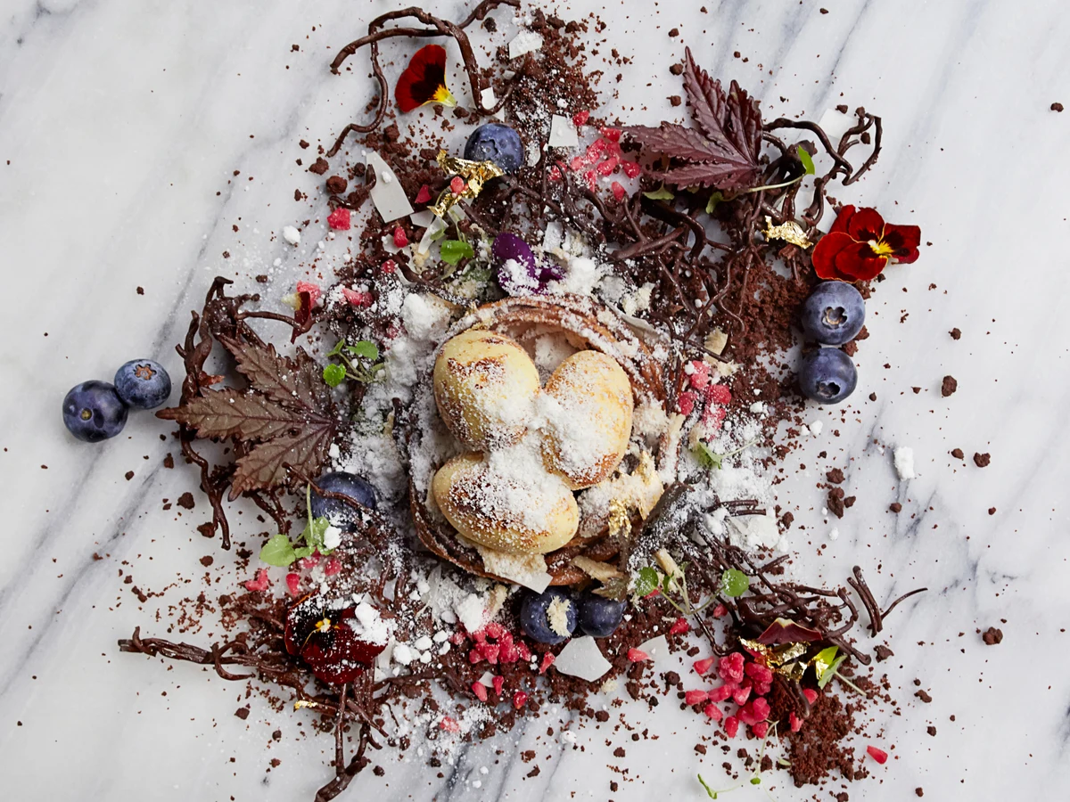Aquavit’s Arctic Bird’s Nest dessert with three parfait eggs, berries and chocolate twigs.