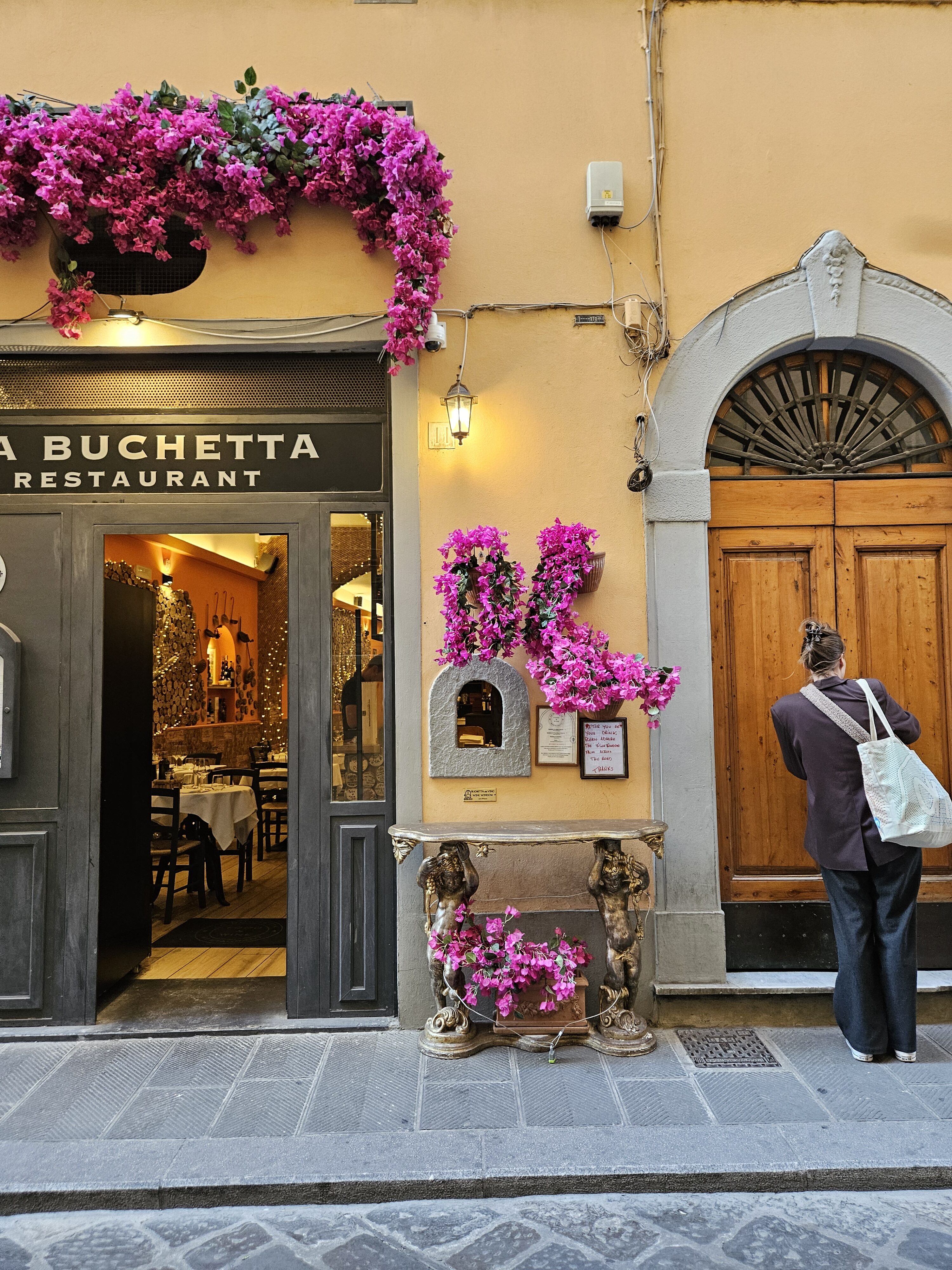 La Buchetta Restaurant storefront with magenta bougainvillea cascading above entrance on yellow-washed Tuscan building